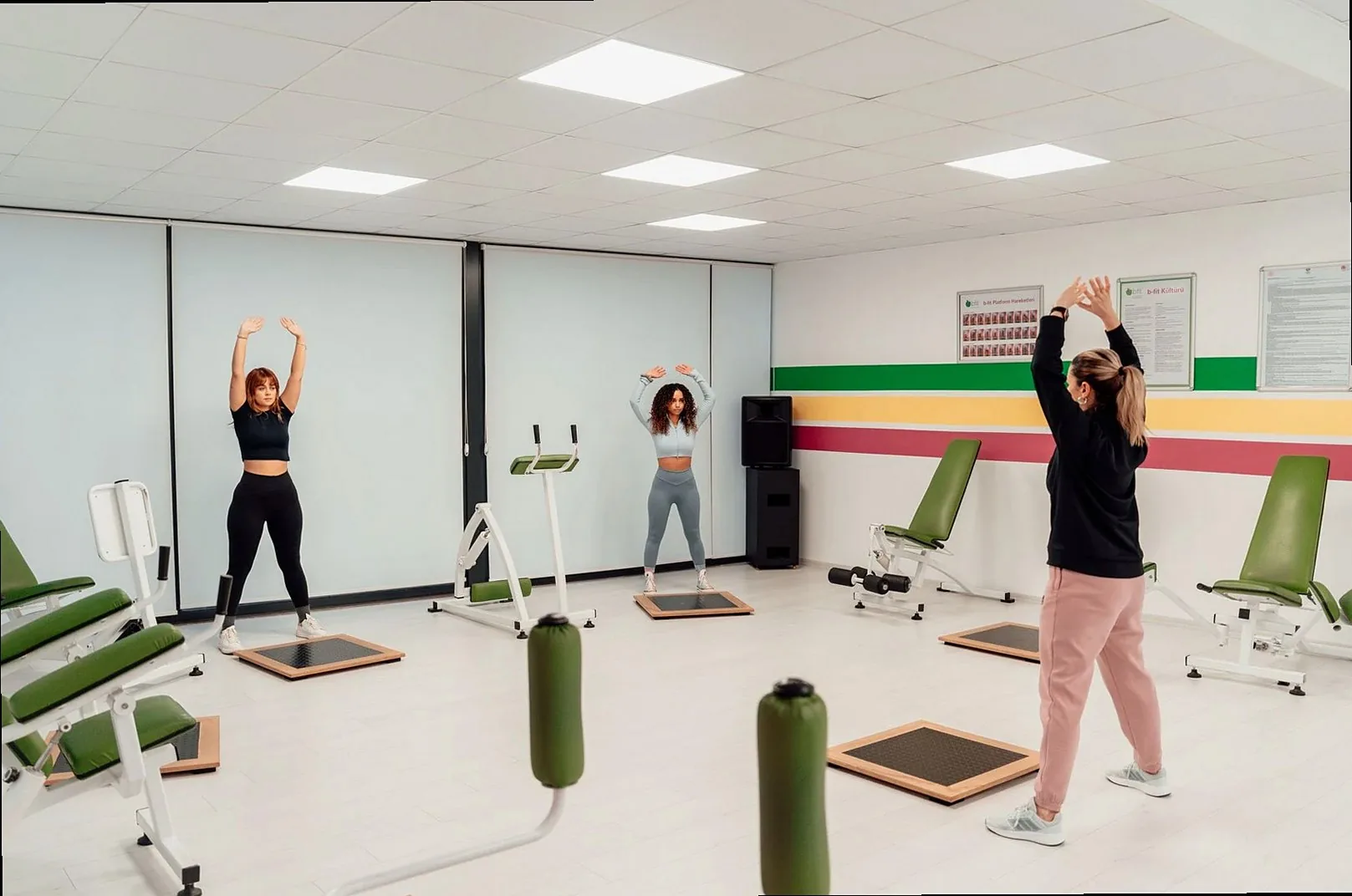 Three women engage in a workout session in a brightly lit, modern fitness studio in Yalova, Türkiye.