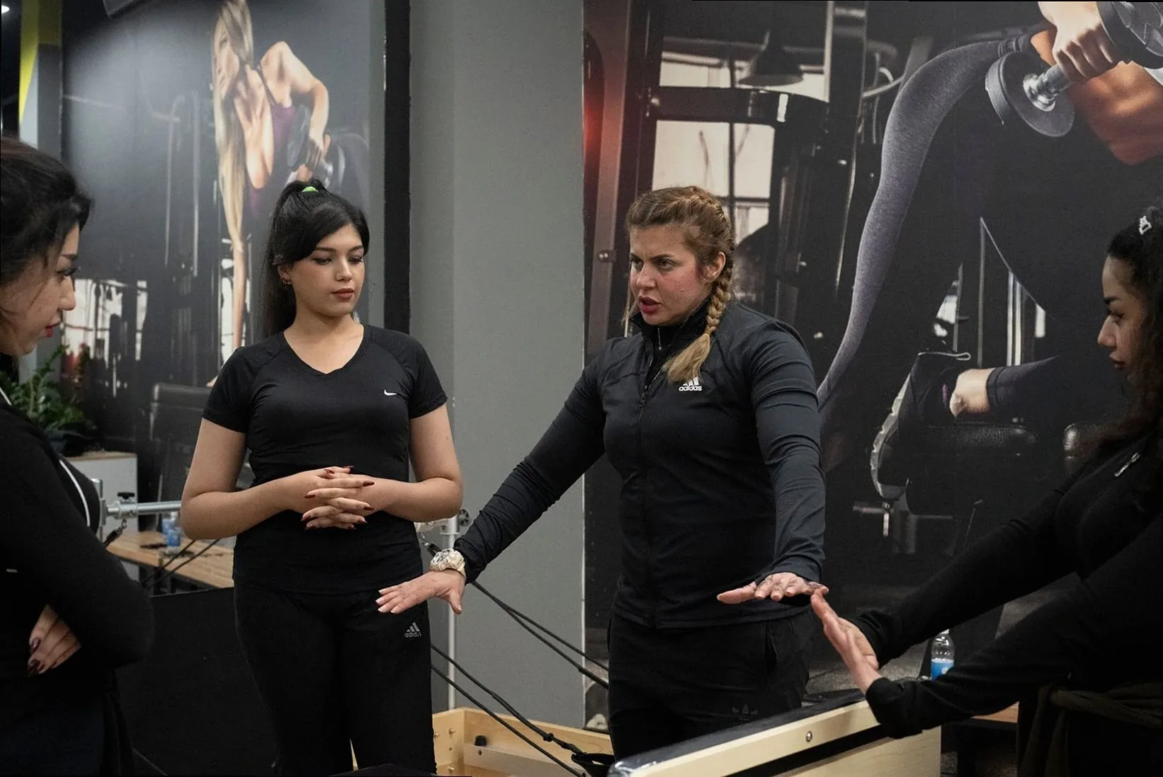 Women participating in a group fitness training session led by an instructor in a gym.